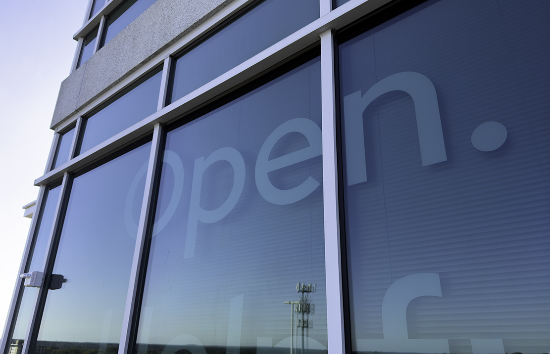 A photo shows a large display of the Red Hat brand personality traits on a window at Red Hat Tower.
