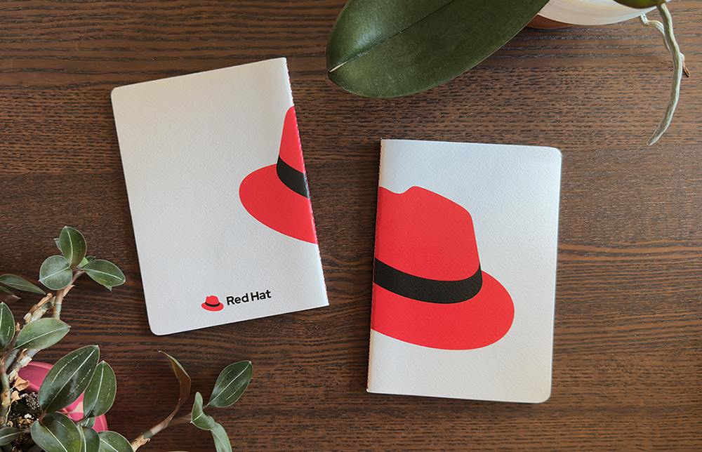 A photo of a notebook with the hat printed over the spine. The front 3/4ths of the hat is on the front and the last 1/4th is on the back.
