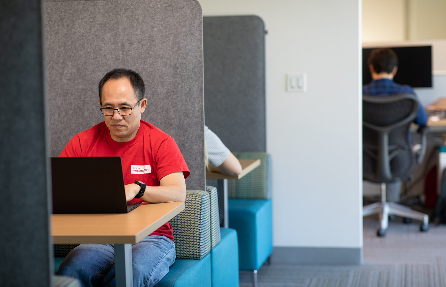 A Red Hatter sitting in an open office space.
