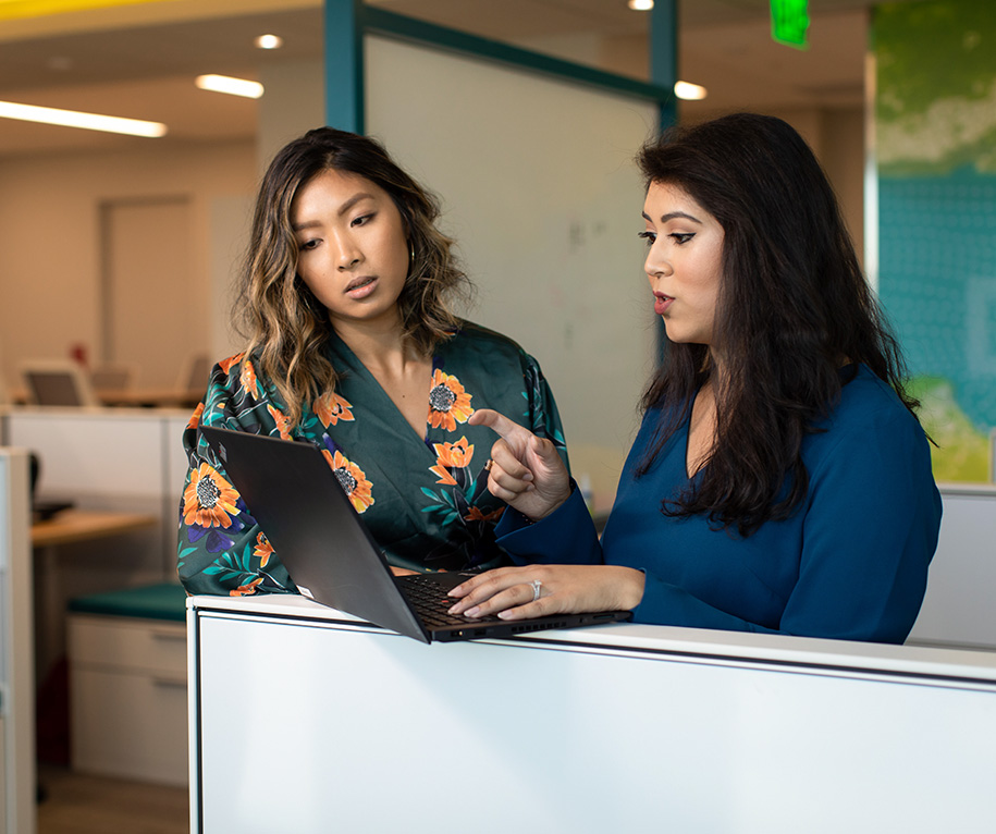 Two office workers looking at a laptop